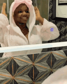 a woman in a bathrobe looks at herself in a mirror