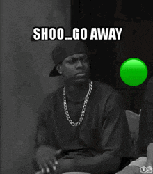 a black and white photo of a man with a green light behind him that says shoo go away