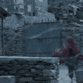 a woman in a red scarf is walking across a stone wall