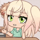 a girl with blonde hair and green eyes is sitting at a desk