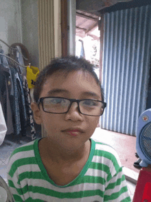 a young boy wearing glasses and a striped shirt looks at the camera