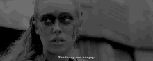 a black and white photo of a woman with a tattoo on her face and the words `` the living are hungry '' .