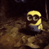 a yellow minion is sitting on a pile of leaves