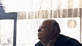 a man wearing glasses looks up at something in the distance