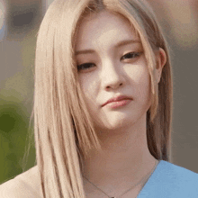 a woman with blonde hair is wearing a blue top and necklace
