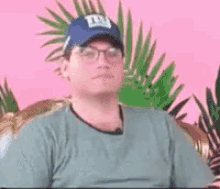 a man wearing a blue hat and glasses is sitting on a couch .