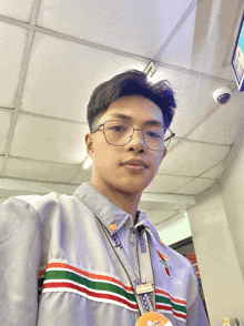 a man wearing glasses and a 7 eleven lanyard takes a selfie