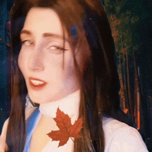 a close up of a woman 's face with a maple leaf on her neck