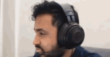 a man wearing headphones and a microphone is sitting on a couch .