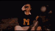 a man wearing a sweater with the number 1 on it is sitting on the ground
