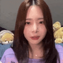a woman with long hair is wearing a purple shirt and looking at the camera .