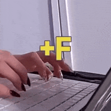 a woman is typing on a laptop with the letter f in the corner .