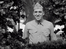 a man in a military uniform stands in front of trees