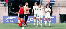 a group of soccer players standing on a field with a sign that says liga f on it
