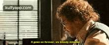 a man with glasses is sitting in front of a window and says it goes on forever six bloody minutes .