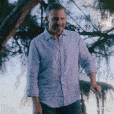 a man in a blue shirt is standing in front of a tree with a netflix logo in the corner