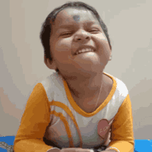 a little girl wearing an orange and white shirt with a pink heart on it