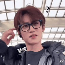 a young man wearing glasses and a jacket has a question mark on his face