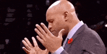 a bald man in a suit and tie is clapping his hands together .
