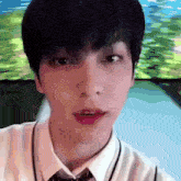 a close up of a young man 's face wearing a white shirt and tie .