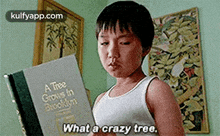 a young boy is reading a book and says `` what a crazy tree '' .