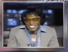 a man in a suit and sunglasses is smiling while wearing headphones and a microphone .