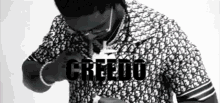 a black and white photo of a man wearing glasses and a shirt with the word creedo on it .