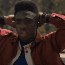 a man wearing a red jacket and a watch looks at something
