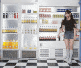 a girl stands in front of a fridge full of sodas including coca cola