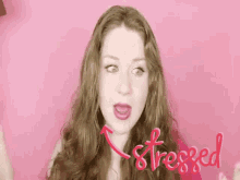 a woman with long red hair is making a funny face against a pink background .