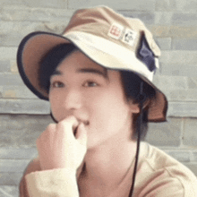 a man wearing a hat with chinese characters on it bites his nails