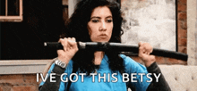 a woman in a blue shirt is holding a sword in her mouth .