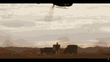 a helicopter is flying over a desert with a man standing in the foreground