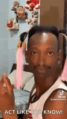 a man with a nose ring is making a funny face while sitting in a bedroom with stuffed animals .
