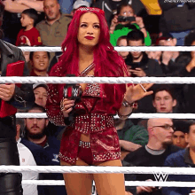 a woman with red hair is standing in a wrestling ring holding a microphone ..