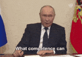 a man in a suit and tie is sitting at a desk and talking about what competence can