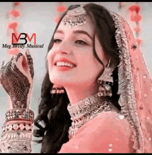 a woman in a pink dress and veil is smiling and wearing a necklace and earrings .