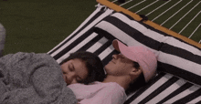 a man in a pink hat and a woman in a pink shirt are sleeping in a hammock