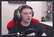 a man wearing headphones is sitting in front of a microphone in a room .