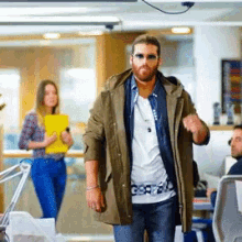 a man wearing sunglasses and a shirt that says gsdf is walking in a room