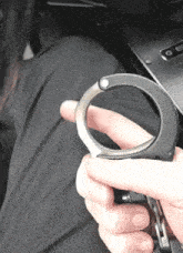 a person is holding a pair of handcuffs between their fingers