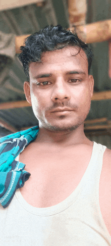 a man in a white tank top has a scarf around his shoulder