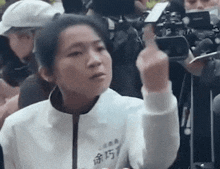 a woman is giving the middle finger to a cameraman while sitting in a crowd of people .