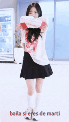 a girl in a white shirt and black skirt is dancing with the words baila si eres de marti