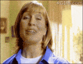 a woman in a blue shirt is smiling with a 4gifs.com watermark