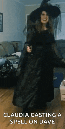 a woman in a witch costume is standing in a living room holding a wand .