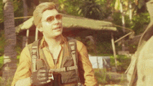 a man wearing sunglasses and a backpack is talking to another person
