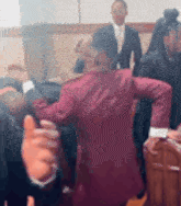 a man in a red suit is dancing in front of a group of people .