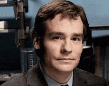 a man in a suit and tie stands in front of a shelf that says ' lithium ' on it
