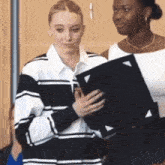 a woman in a striped shirt holds a black folder